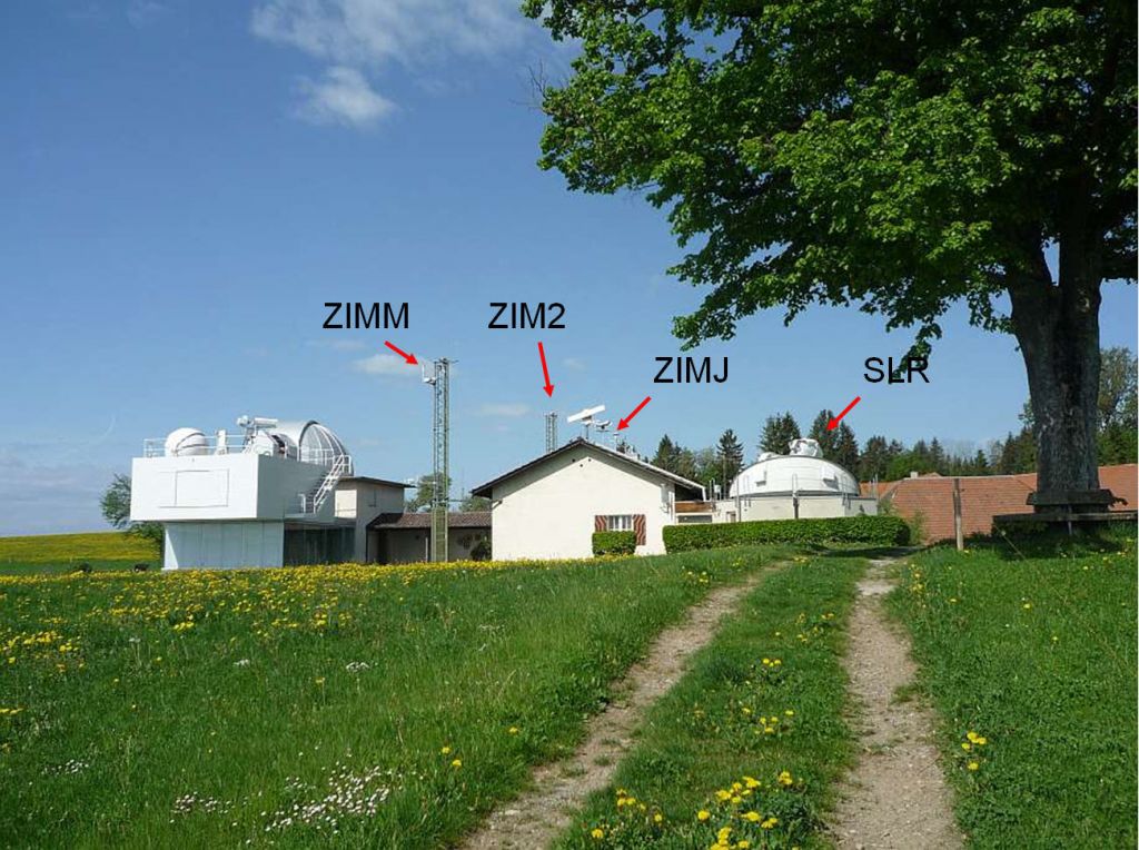 on the left hand side the twin telescope with the 40 cm Schmidt camera and the 60 cm Cassegrain can be seen through the opened dome. The antenna of the permanent GPS receiver (owned and operated by the Federal Office of Topography) is mounted on the 9-meter steel mast. The main house contains a kitchen, a living room, a bed room, a bath, and a computer room. On the roof there are the aircraft detection radar and several additional monuments for GPS and GLONASS antennae. To the right you see the opened SLR dome with ZIMLAT, the ZIMmerwald Laser and Astrometric Telescope.
