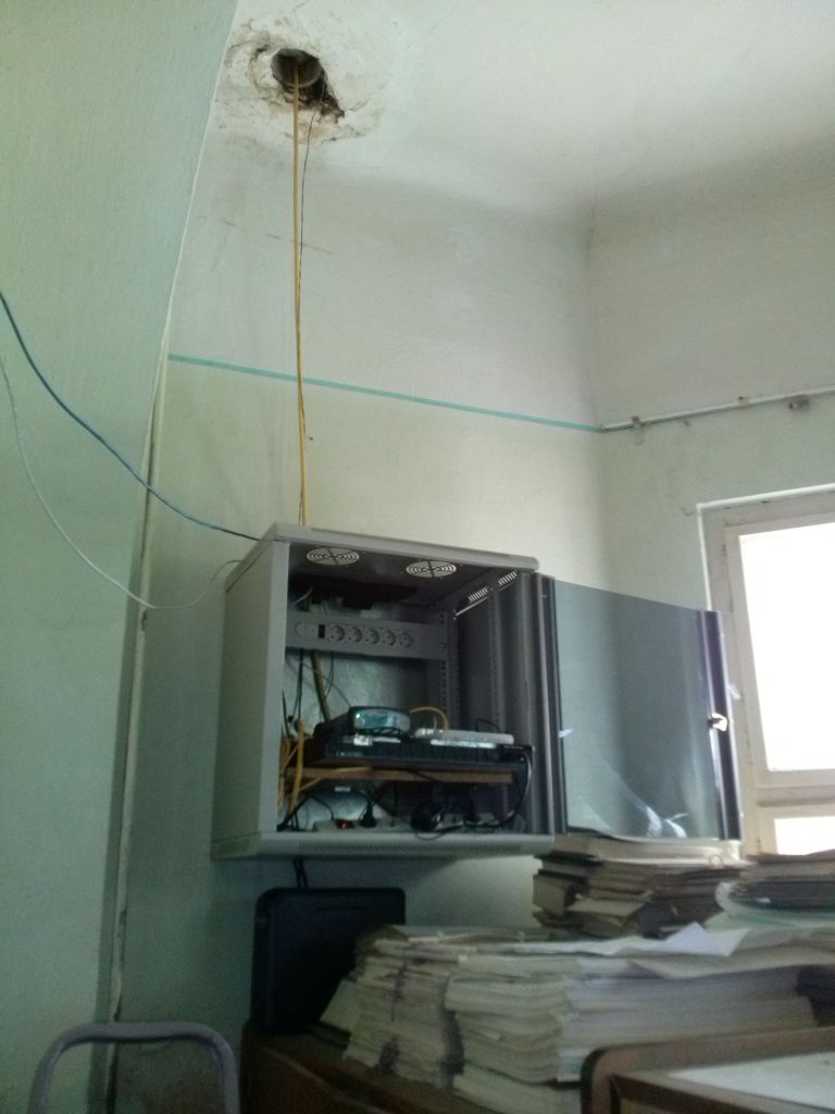 A closer view of the rack cabinet where Trimble NetR9 GNSS receiver is placed along with other reference station modules in local cadastre office. The belonging antenna cable and ethernet LAN cable are visible in the picture.