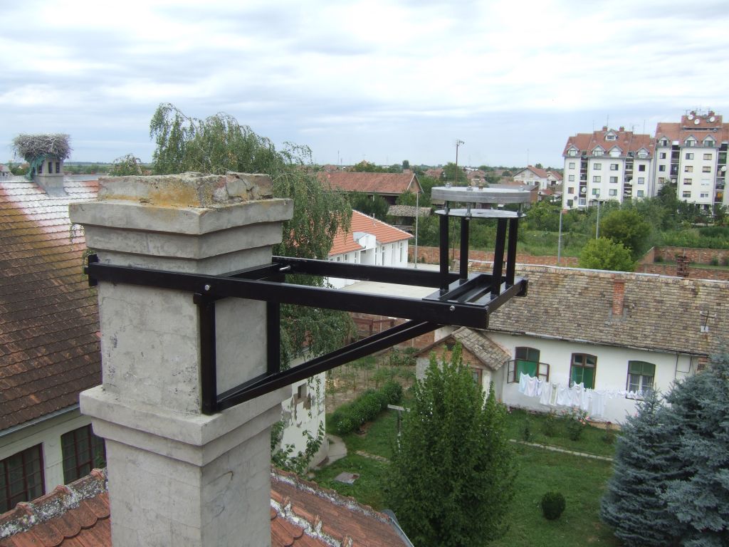 The close view of the metal console attached to the concrete chimney on the roof of local cadastre in Plandiste, with GNSS antenna mounting plate