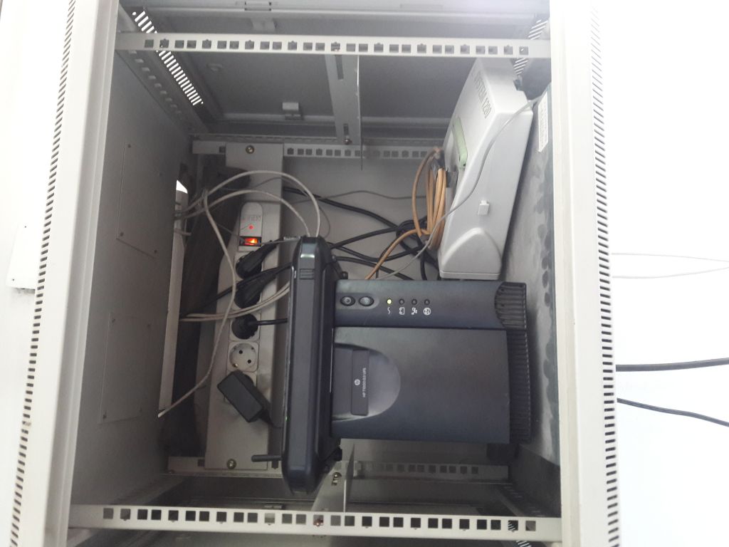 The picture of RAC cabinet with old Leica GNSS receiver LEICA GRX1200GGPRO with belonging Ethernet and power supply equipment. The CORS receiver is located in the offiice of local cadaster building.