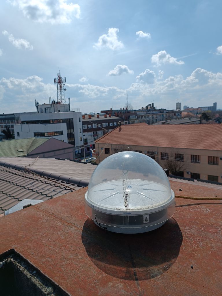 Trimble CORS antenna TRM115000.00 with TZGD protective radome installed on iron console attached on brick chimney on local cadaster building roof.