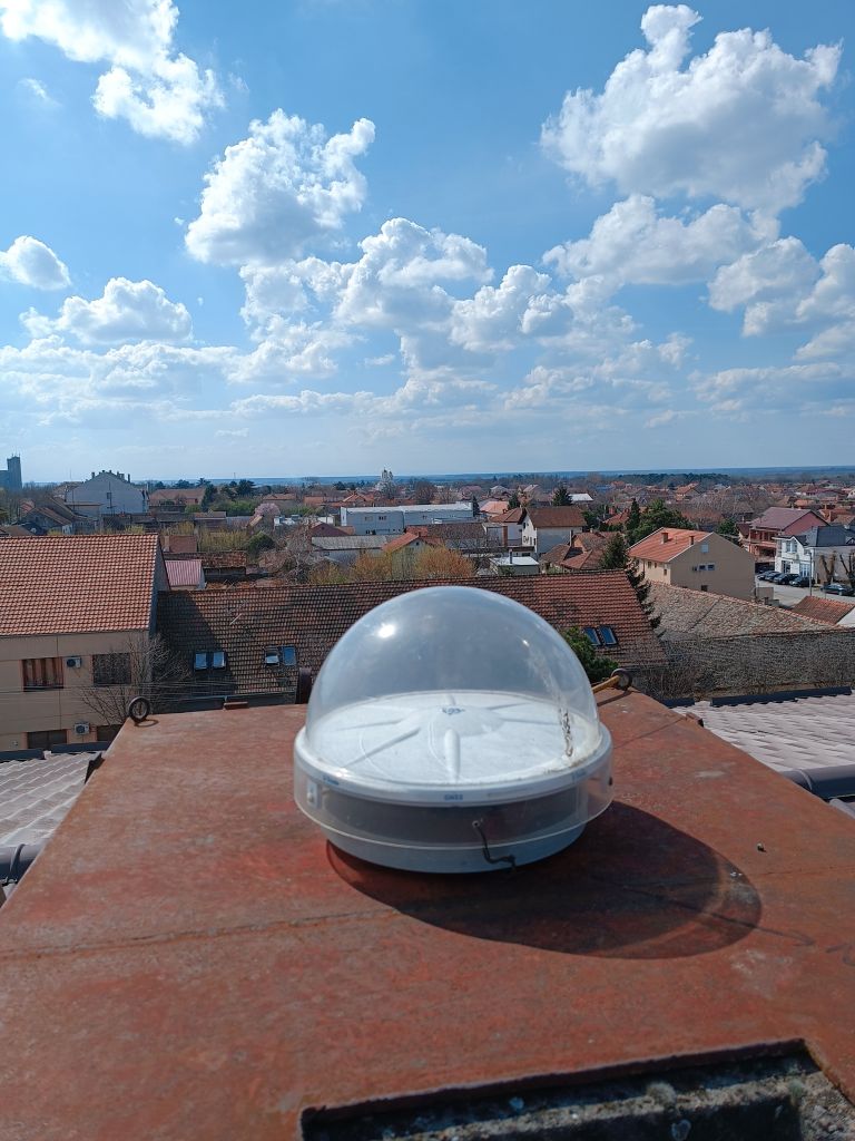 Trimble CORS antenna TRM115000.00 with TZGD protective radome installed on iron console attached on the brick chimney on local cadaster building roof.